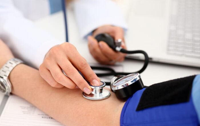 Focus Is On A Doctor Taking A Patient'S Blood Pressure During A Medical Exam. Both Parties Are Unidentifiable.