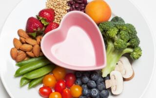 heart shaped dish with fruits, seeds, nuts, and vegetables surrounding it