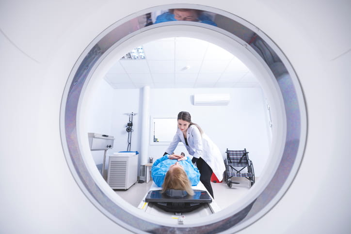 A Doctor Helping A Woman Get Ready On The Table Of A Ct Scan Before She Has Her Lungs Screened. 