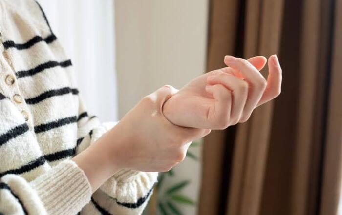 Woman In Striped Sweater Holding Wrist In Pain