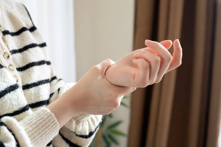 Woman In Striped Sweater Holding Wrist In Pain