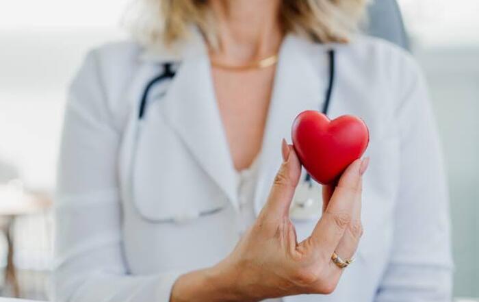 Female Doctor In White Coat Holding A Red Heart